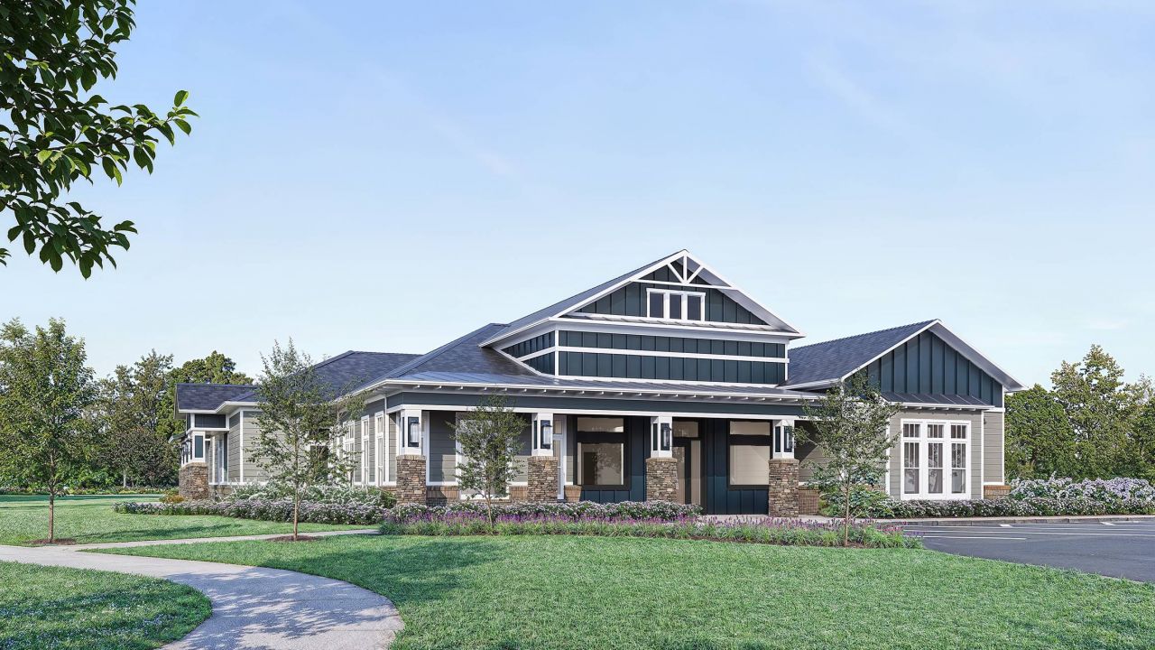 The exterior of the clubhouse at Hawthorne at Holbrook, featuring a craftsman-style design with dark siding, stone accents, and surrounding green landscaping.