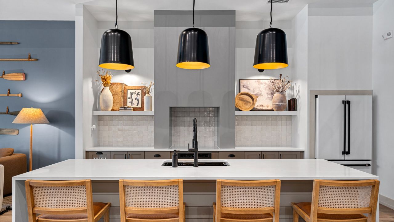 a modern kitchen with marble counter top, recessed lights, and high chairs